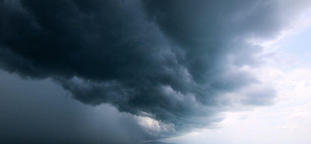 Mörka stormmoln drar in över ett oroligt hav vid kusten