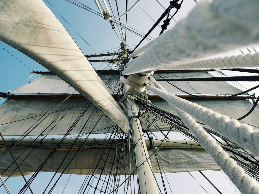 Närbild under segelbåtens mast med segel, stag och många linor